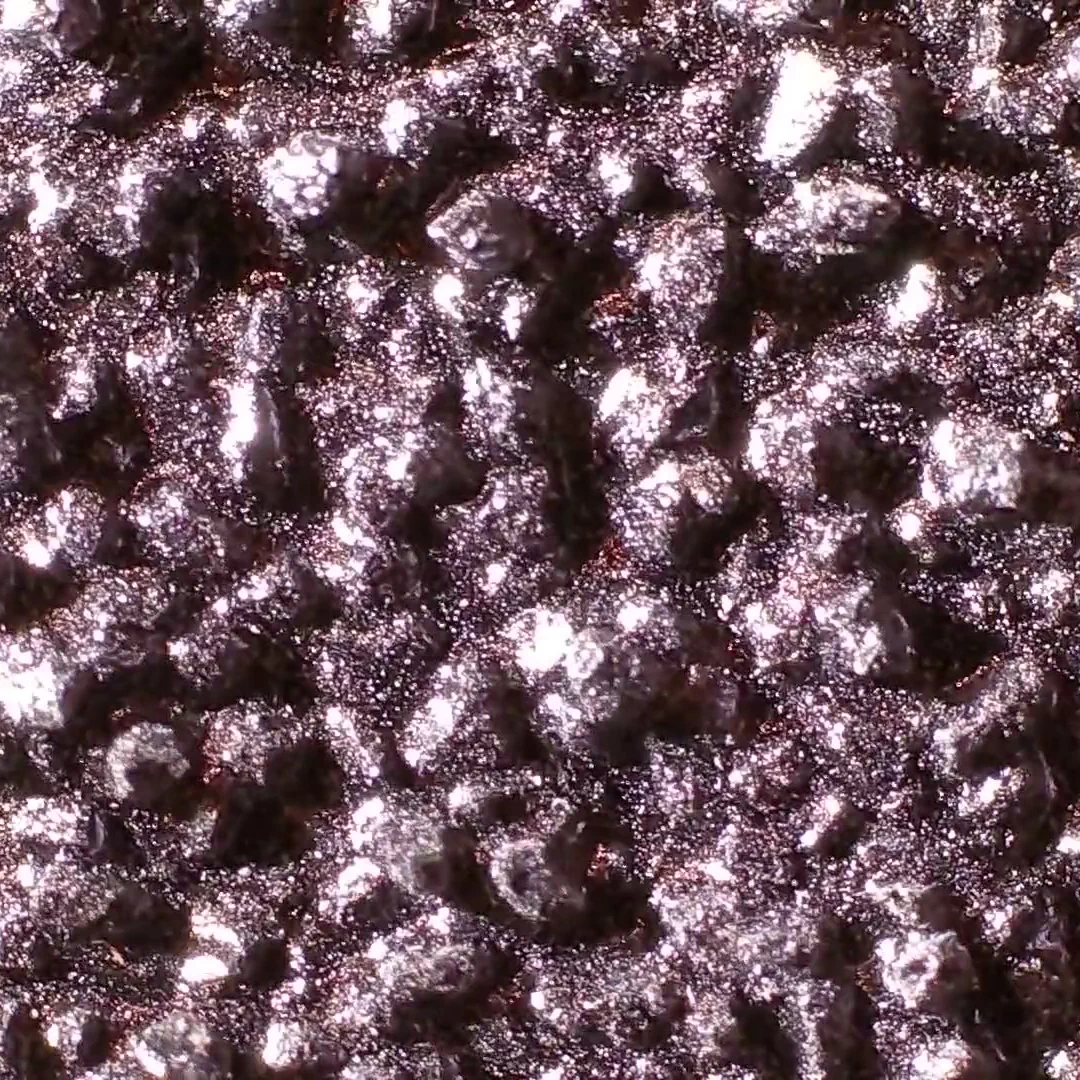 Magnified view of 80 grit silicon carbide sandpaper, showing black crystals over a black glued backing