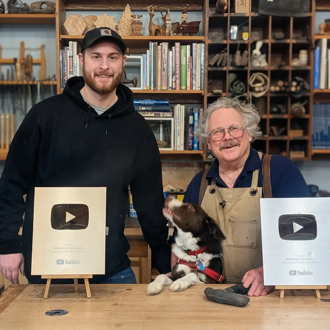Slide 1 - Travis Blair, Bella the dog, and Nick Engler standing behind a 100k and 1m YouTube subscriber plaque